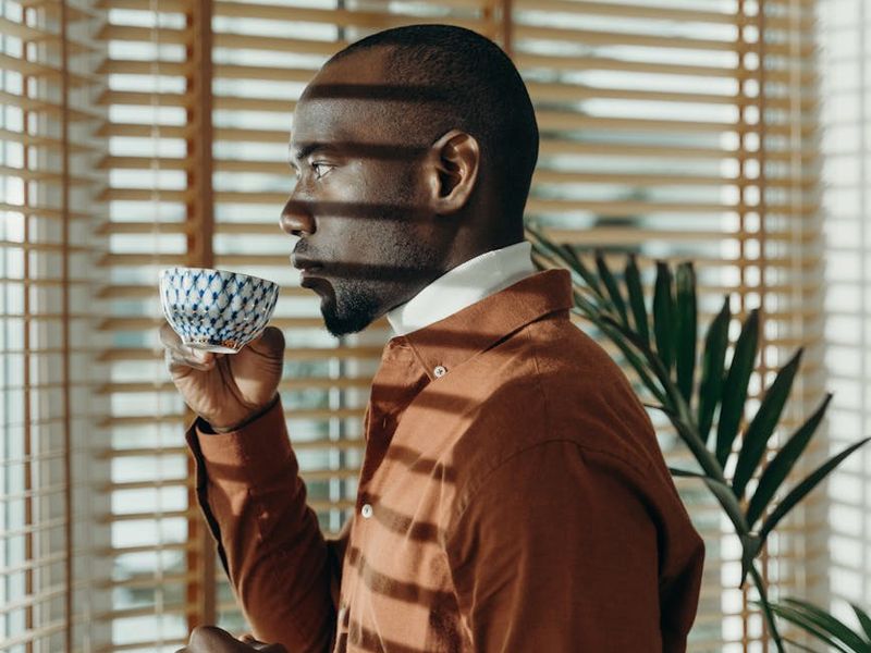 Person calmly drinking tea and looking out a window.